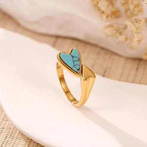 Vue macro d'une bague coeur dorée rétro avec pierre turquoise bleue et métal poli