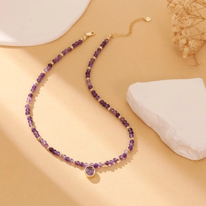 Detail of amethyst beaded necklace with a round purple pendant and golden lobster clasp