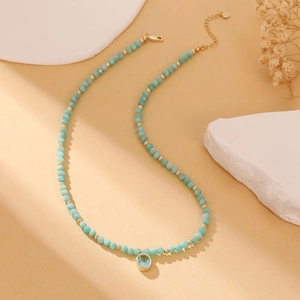 Close-up of matte light blue natural stone beads and golden oval gemstone pendant