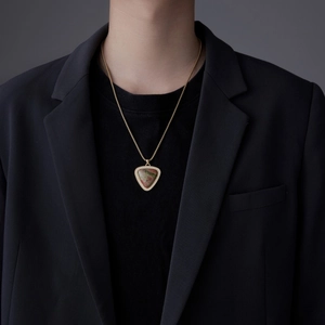 Collier homme doré avec pendentif bouclier en unakite verte porté sur un costume noir