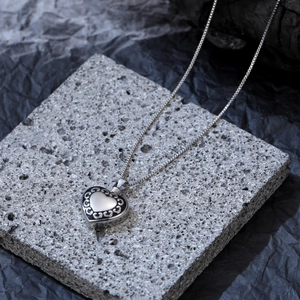 Macro di una collana a cuore in argento con dettagli in filigrana su sfondo di roccia