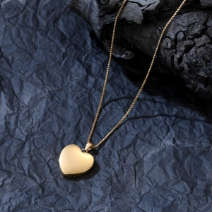 Dettaglio di un medaglione a cuore dorato con catena box su fondo scuro strutturato