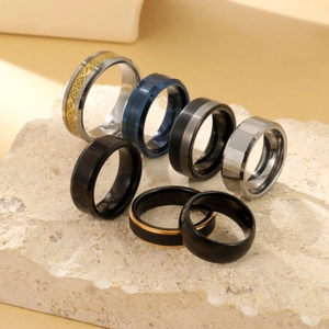 Macro di anelli in acciaio al tungsteno in nero, blu e argento su base di roccia