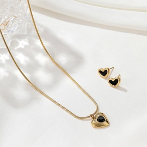 Detailansicht von goldenem Herz-Schmuckset mit Kette und Ohrringen mit schwarzem Email