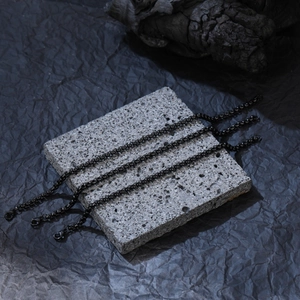 Détail de bracelets à chaîne box noire avec fermoirs mousquetons sur pierre