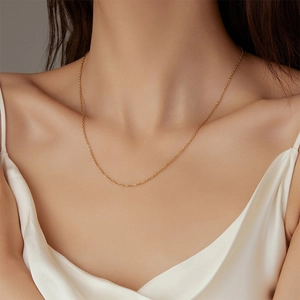 Gros plan d'un collier chaîne à maillons minimaliste plaqué or 18k sur le cou
