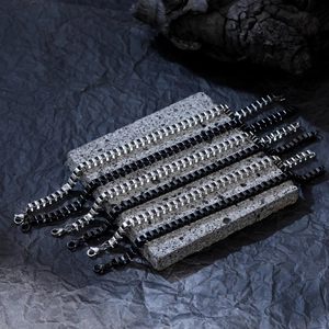Bracelets gourmette carrés en argent et noir sur un support en pierre texturé