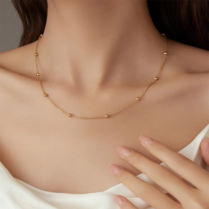 Détail d'un collier chaîne à perles minimaliste plaqué or 18 carats sur le cou d'un mannequin