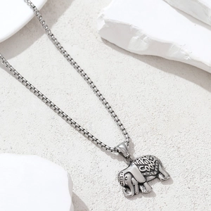 Vintage stainless steel elephant pendant necklace on minimalist stone background
