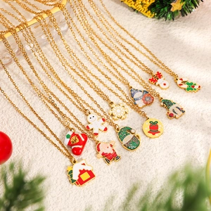 Detailansicht weihnachtlicher Emaille-Anhänger mit Goldketten auf weißem Plüschhintergrund