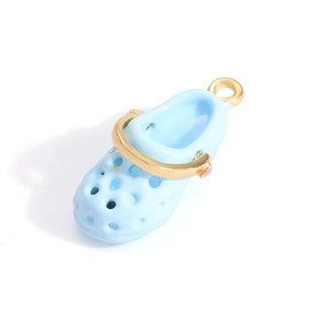 Macro detail of a light blue mini clog charm with golden accents and top loop