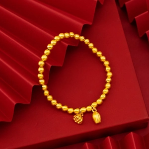 Dettaglio di ciondoli a loto in oro opaco e bocciolo su bracciale di perline