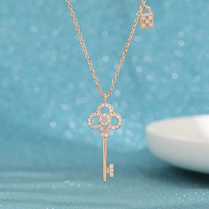 Elegant rose gold key and padlock necklace with crystals on dreamlike blue background