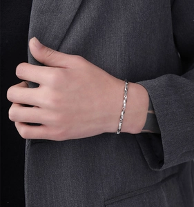 Dettaglio del bracciale Mobius in argento da uomo indossato con un abito grigio chic