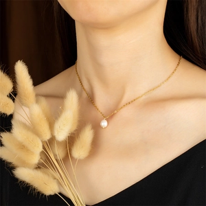 Elegante gouden ketting met een druppelvormige parelhanger op een vrouwelijk model