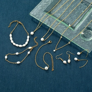 Elegante parelsieradenset met gouden kettingen en armbanden op een blauwe stoffen achtergrond