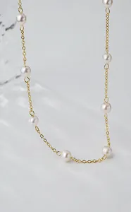 Detailweergave van de elegante gouden schakelketting met ronde zoetwaterparels
