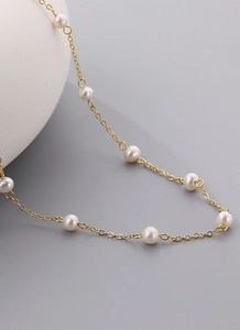 Macro detail van een vergulde ketting met glanzende witte zoetwaterparels voor dames