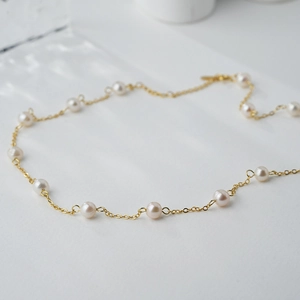 Elegante gouden ketting met ronde witte zoetwaterparels in een modern en minimalistisch design