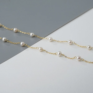 Elegante gouden ketting met ronde witte parels getoond in een gedetailleerde close-up