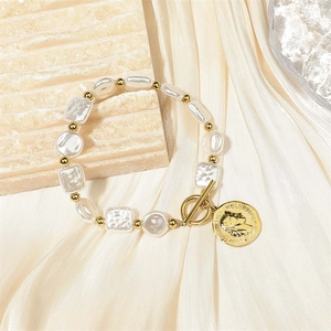 Barockperlenarmband mit Goldmünzenanhänger und OT-Verschluss auf cremefarbener Seide