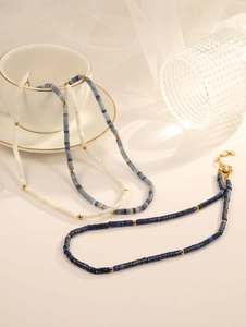 Close-up of Bohemian beaded necklaces with blue stone beads and gold lobster clasps
