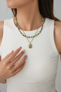 Close-up of layered necklace with colorful beads and a gold snake pendant on a model