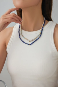 Detail of layered bohemian necklace with blue beads and gold accents on a model