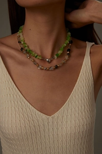 Close-up of stacked natural stone necklaces with a silver heart charm and black crystals