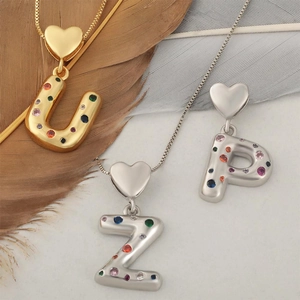 Dettaglio di ciondoli a cuore con lettere, zirconi colorati e placcatura in oro