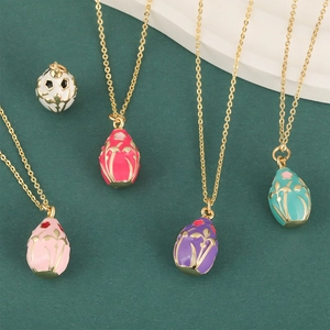 Five colorful 18K gold plated oval floral enamel pendant necklaces on a green display