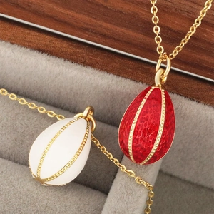 Elegant Russian-style egg pendants in red and white enamel with gold chains in a jewelry box