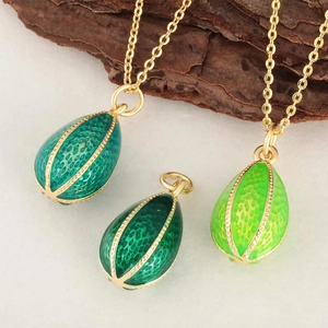 Enamel egg pendants in three green shades with gold chains on natural tree bark background