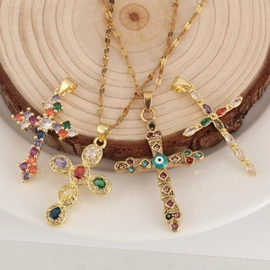 Gold cross pendant necklaces with colorful zircon stones on a rustic wood background