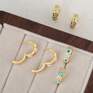 Golden huggie hoop earrings with colorful evil eye charms and sparkling zircon stones