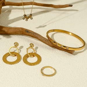 Vergulde sieradenset met zirkoon oorbellen, armband, ring en ketting op houtdecor