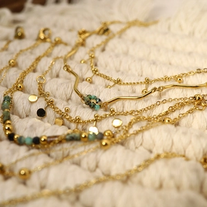 Detail of bohemian gold chains with turquoise beads on a soft knit background