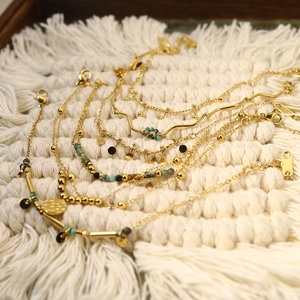Detail of gold titanium steel bracelets with turquoise beads and unique charms on white fabric