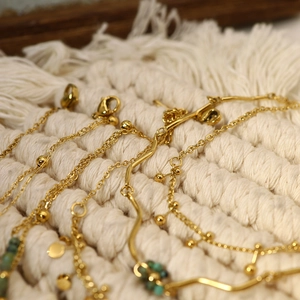 Macro shot of gold-plated bracelets featuring turquoise beads and metal lobster clasps