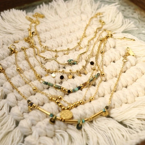 Bohemian gold bracelets with turquoise beads and coins on a white woven background