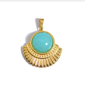 Macro d'un pendentif éventail doré orné d'une pierre naturelle ronde turquoise