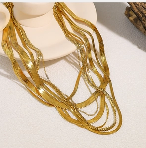 Detailed view of layered golden stainless steel snake chains on a ceramic tray