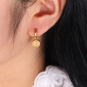 Gros plan sur boucle d'oreille créole 18K dorée avec pierre rose sur mannequin