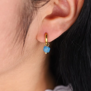 Détail d'une boucle d'oreille plaquée or 18K avec pendentif en pierre bleue brute