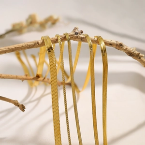 Minimalist gold stainless steel snake and blade necklaces hanging on wooden branch