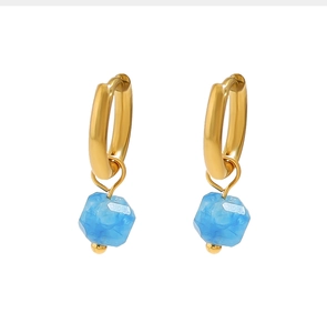 Détail de boucles d'oreilles créoles en or 18 carats avec pendentifs en pierre bleue