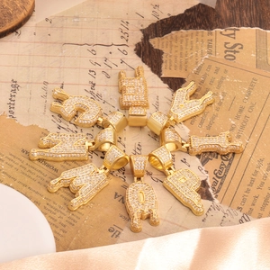 Macro view of gold plated hip hop drip letters pendants with sparkling white zircons
