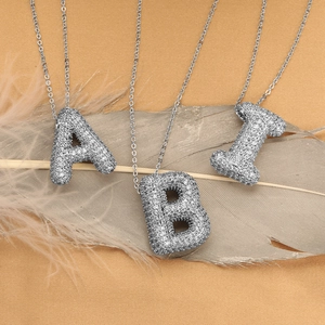 Ciondolo a lettera 3D color argento con zirconi scintillanti su piuma morbida