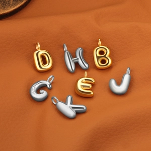Détail des pendentifs lettres 3D dorés et argentés sur un support en cuir marron