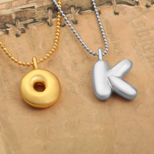 Détail des pendentifs lettres O dorée et K argentée style ballon sur papier